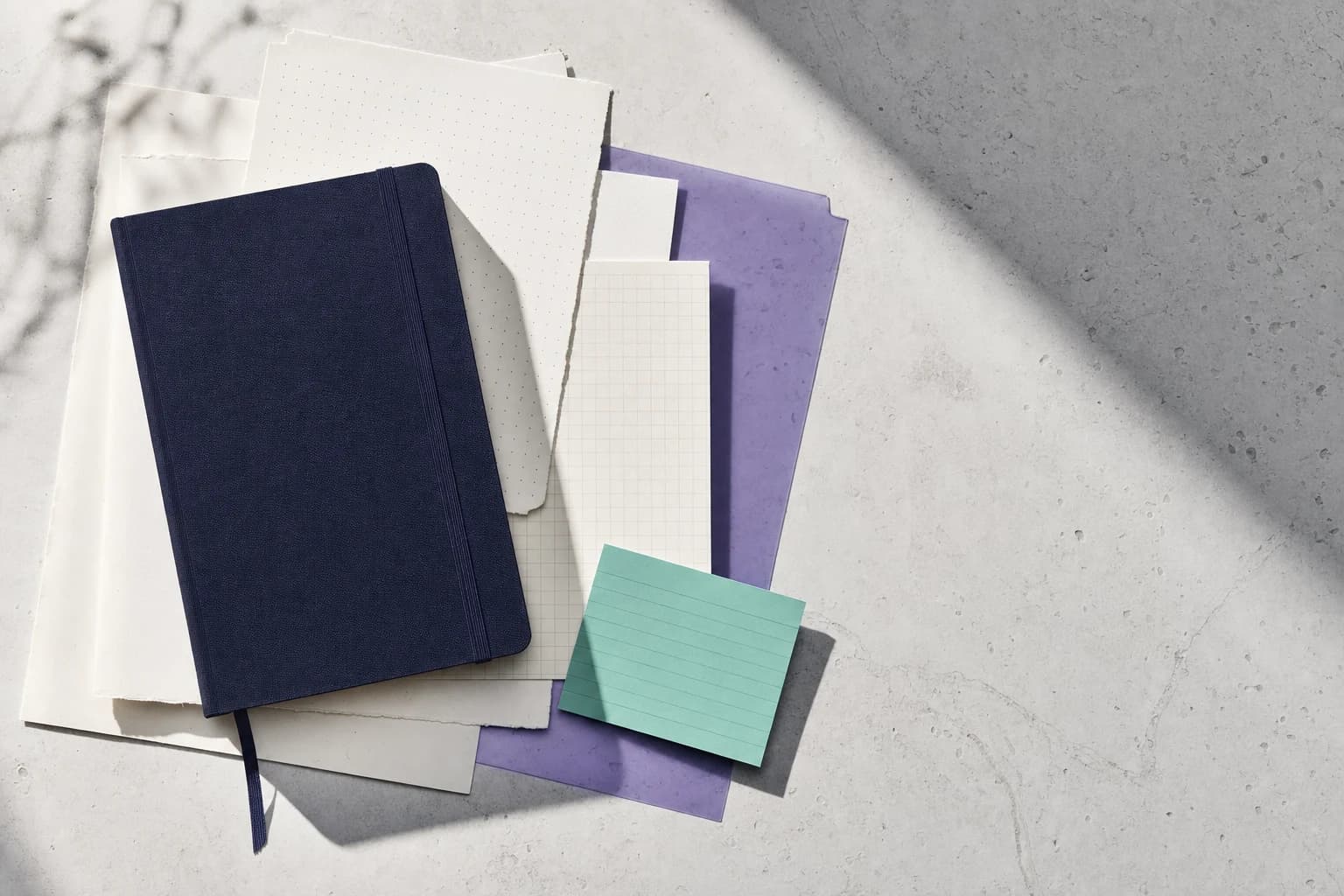 A navy notebook and colored research notes arranged on a stone desk